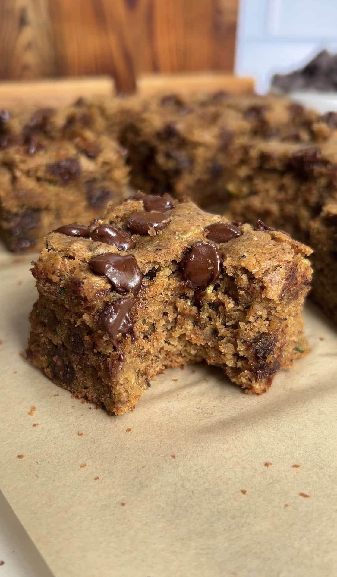 Stack of thick gluten‑free zucchini blondies with glossy chocolate chips, highlighting moist, fudgy texture.