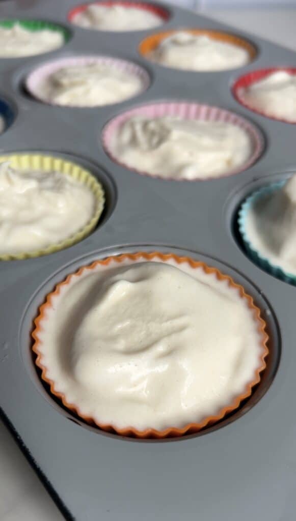 Close‑up of silicone muffin liners filled with smooth vanilla protein ice cream mixture before adding toppings