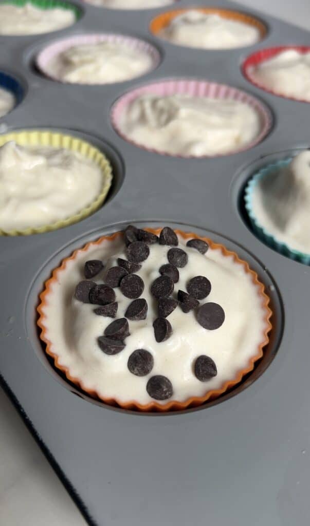 Cookie dough cups topped with vanilla protein ice cream and sprinkled with mini chocolate chips before freezing