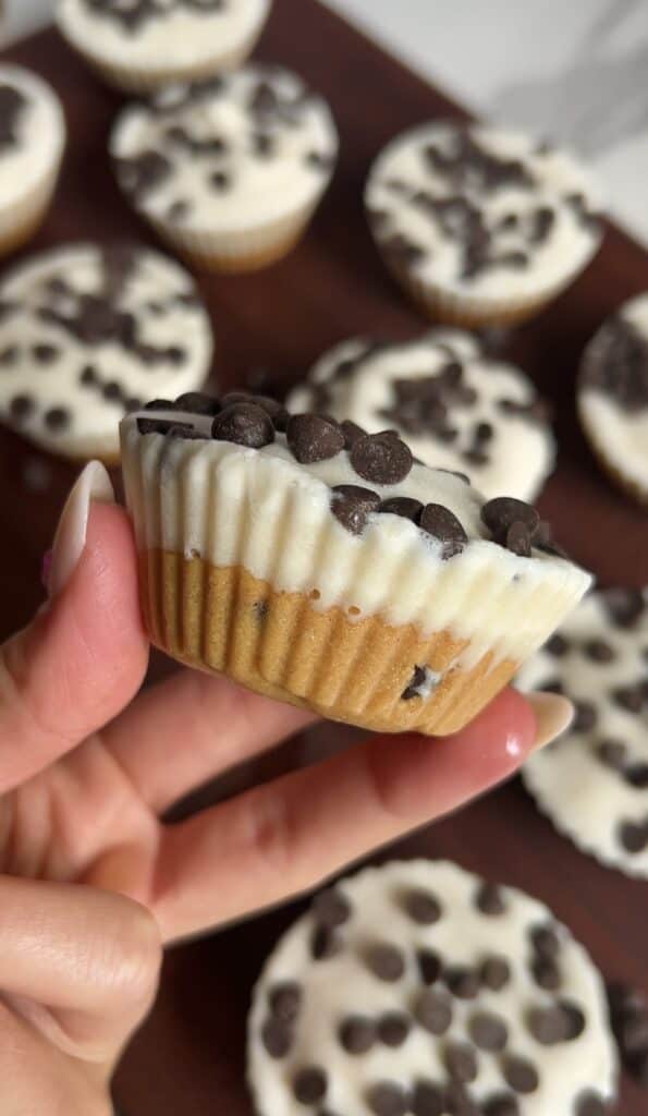 Hand holding a cookie dough ice cream cup showing the layered peanut butter cookie dough base and creamy vanilla top