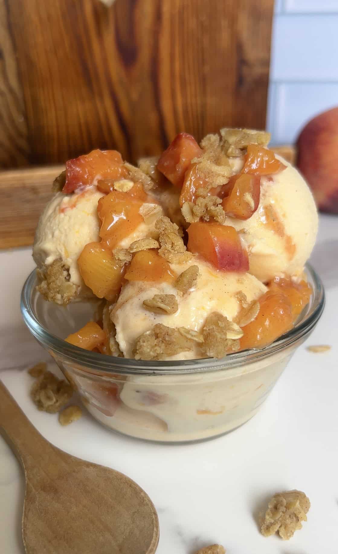 Scoops of high‑protein peach cobbler ice cream with caramelized peaches and oat crumble