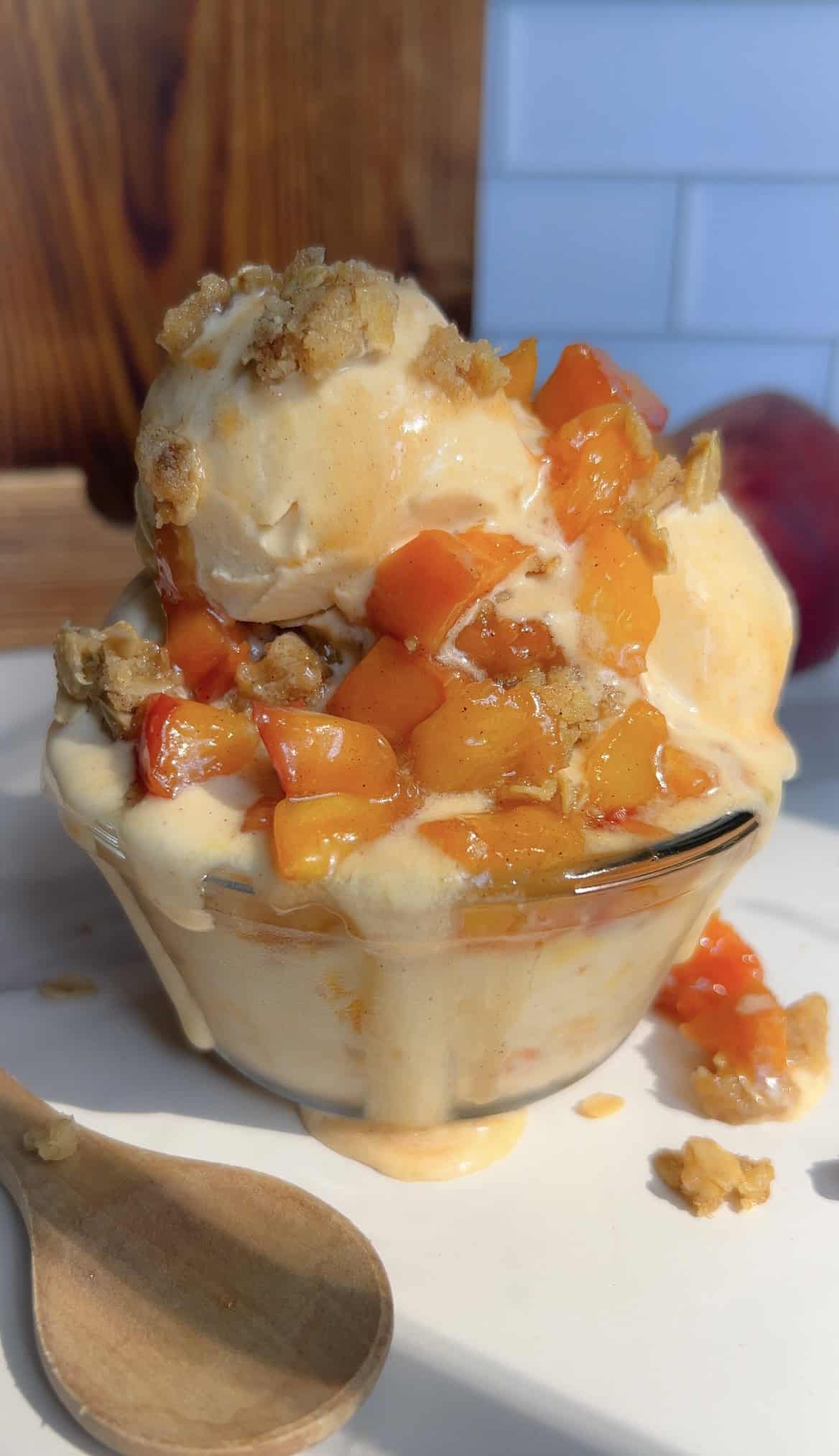 High‑protein peach cobbler ice cream topped with warm caramelized peaches and crumble