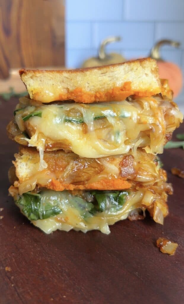 Stacked cheesy vegetable sandwiches with melted cheese and fresh greens.