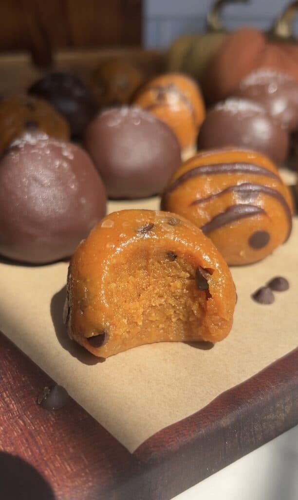 Close-up of dairy-free pumpkin cookie dough truffles with chocolate drizzle.