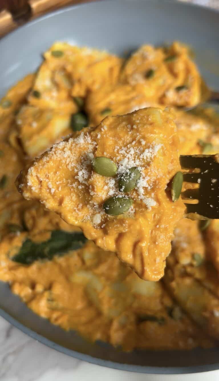 Pumpkin ravioli with cheese and pumpkin seeds in a blue bowl.