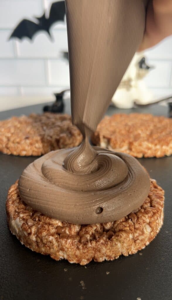 Chocolate Yogurt Mixture being piped onto a rice cake for a Halloween snack.