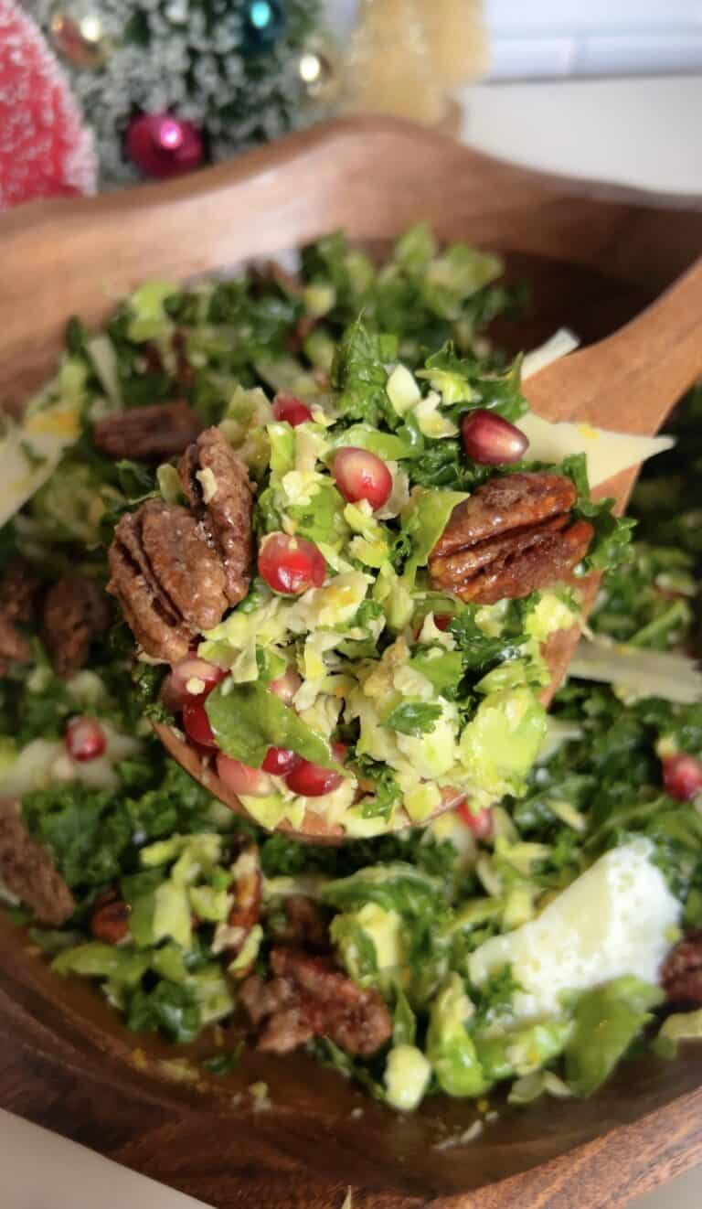 Fresh shaved Brussels and kale salad with pomegranate and candied pecans in a wooden bowl.
