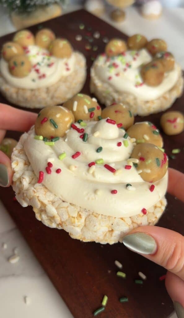 Healthy protein cookie rice cake with white frosting and sprinkles.